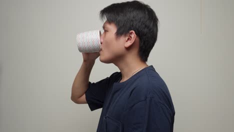 chinese man drinking from a cup, it could be coffee, water, tea, or any other beverage