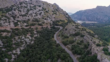 Sinuosa-Carretera-De-Paso-De-Montaña-A-Través-De-Un-Paisaje-Rocoso-Verde,-Drone-Aéreo