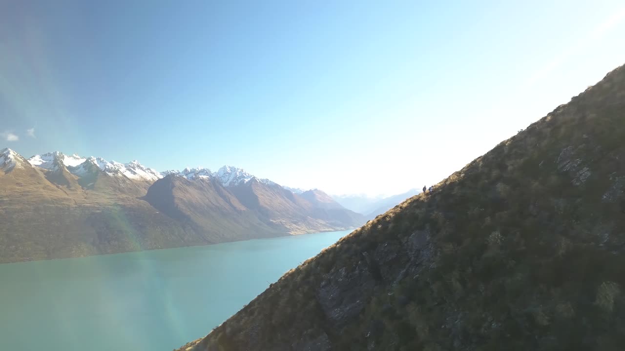 pareja aventurera caminando por la cresta, panorama sobre el paisaje montañoso en nueva zelanda