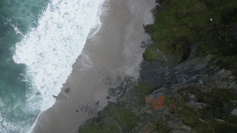 aerial drone shot of sea waves crashing on sandy beach