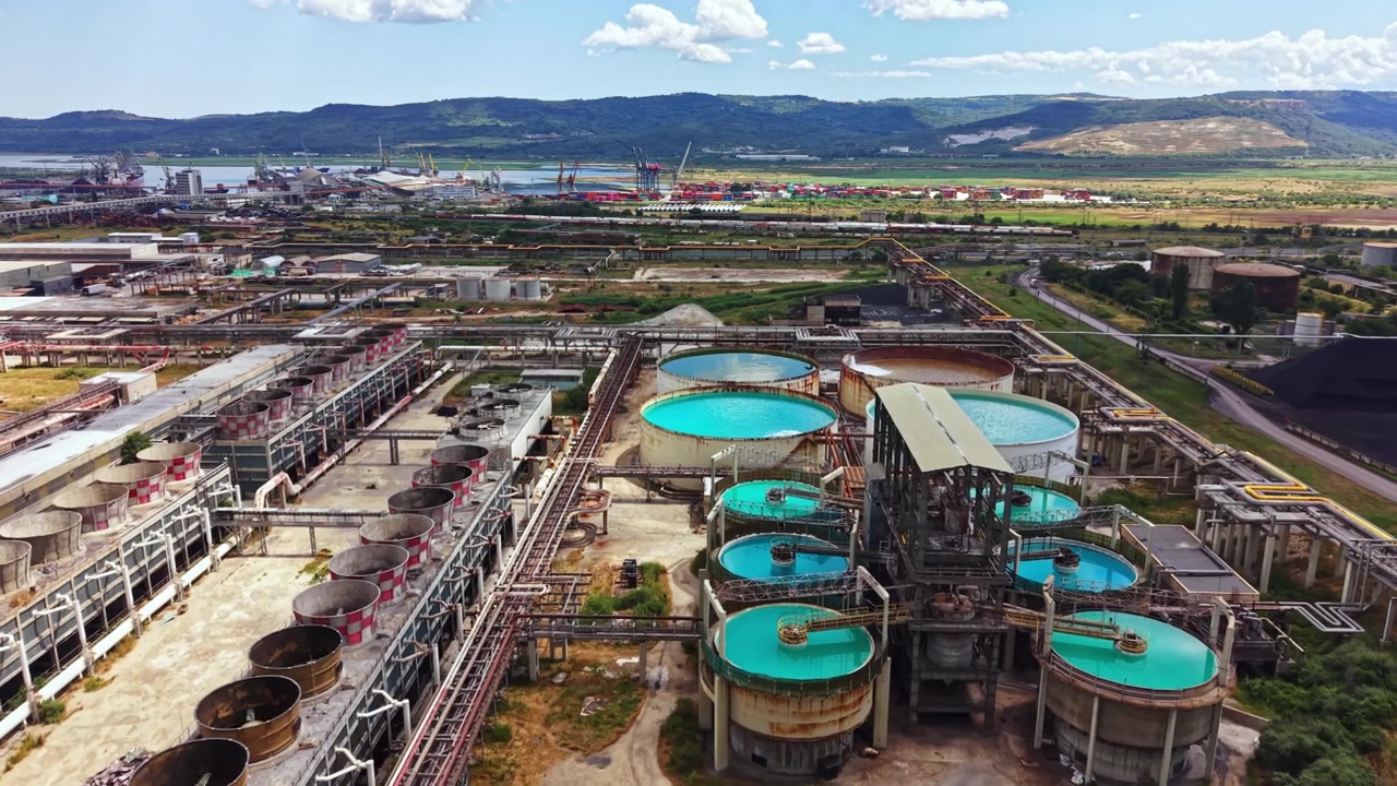 Instalación industrial ubicada cerca de un río con varias estructuras y equipos bajo un cielo despejado durante el día