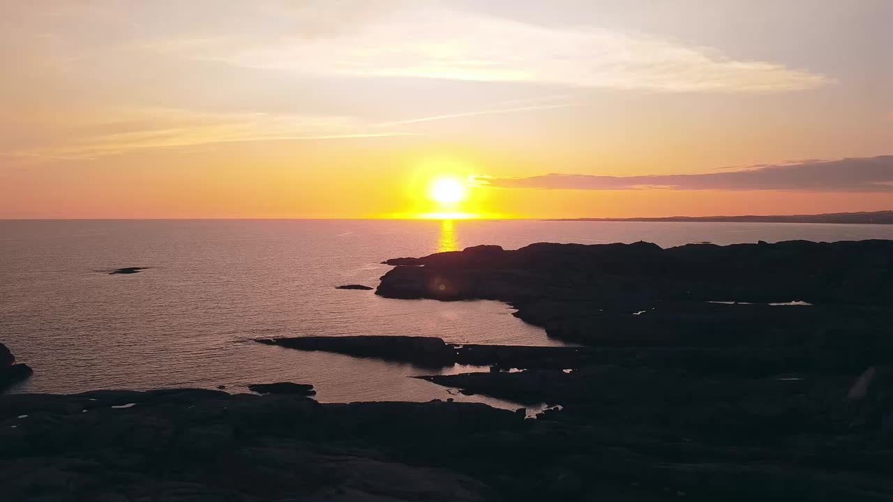 Belo pôr do sol na Noruega sobre rochas no mar, drone, laranja, hora dourada.