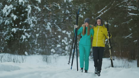 Full-length-portrait-of-active-young-couple-enjoying-skiing-in-snowy-winter-forest,-focus-on-smiling-woman-in-front,-copy-space