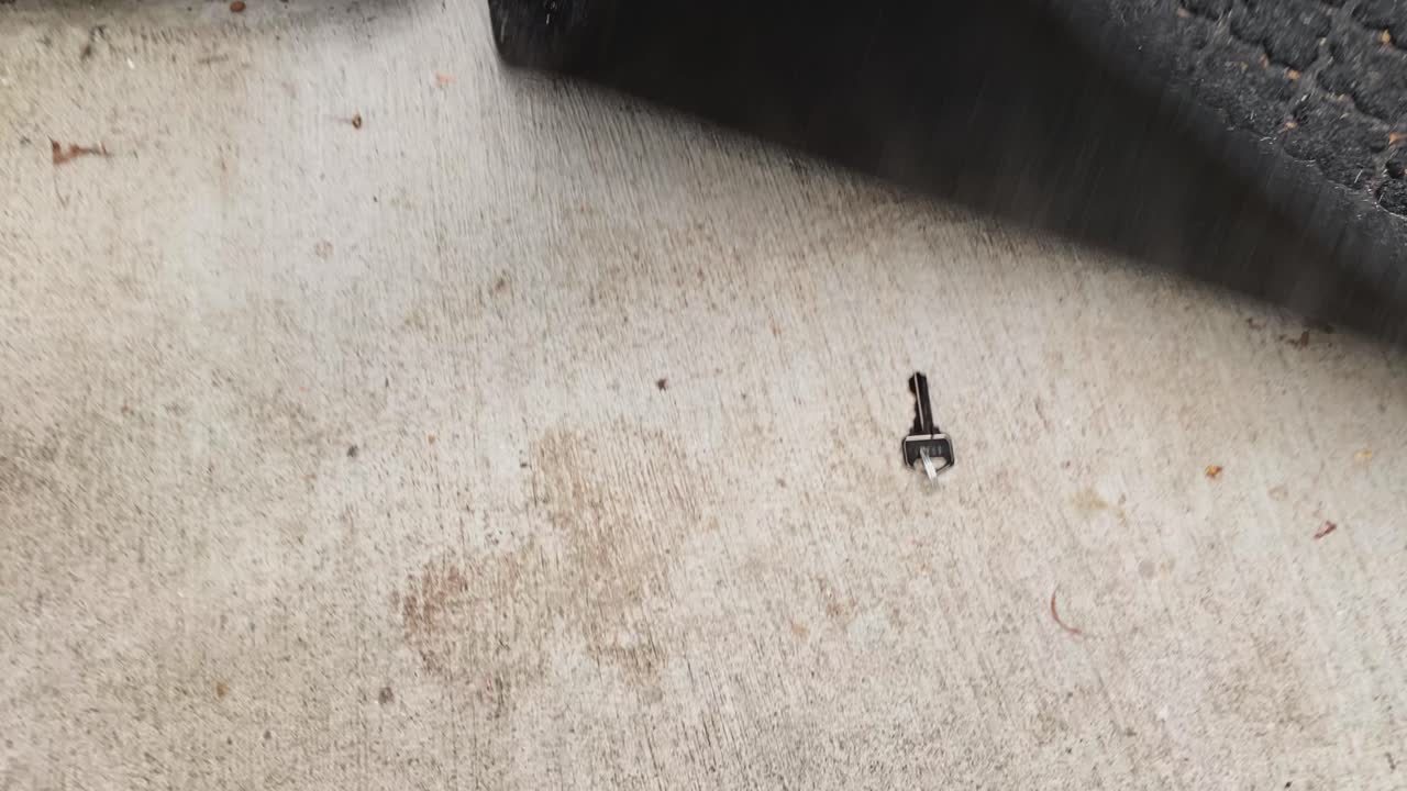 punto de vista caminando hacia una puerta en el costado de una casa con una alfombra de entrada negra y agachándose debajo de la alfombra para encontrar una llave para abrir la puerta de la casa