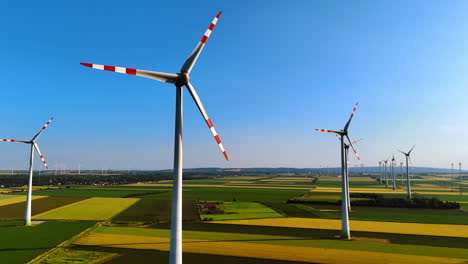 wind turbines produce clean energy. tall wind turbines rotate in a clear sky above vast green and yellow fields, highlighting renewable energy's promise