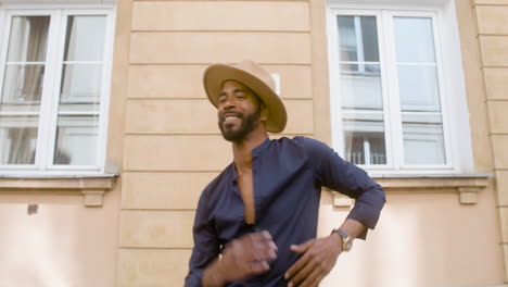 Hombre-Afro-Caribeño-Sonriente-Con-Sombrero-De-Panamá-Bailando-Coreografías-Latinas-Solo-En-La-Calle