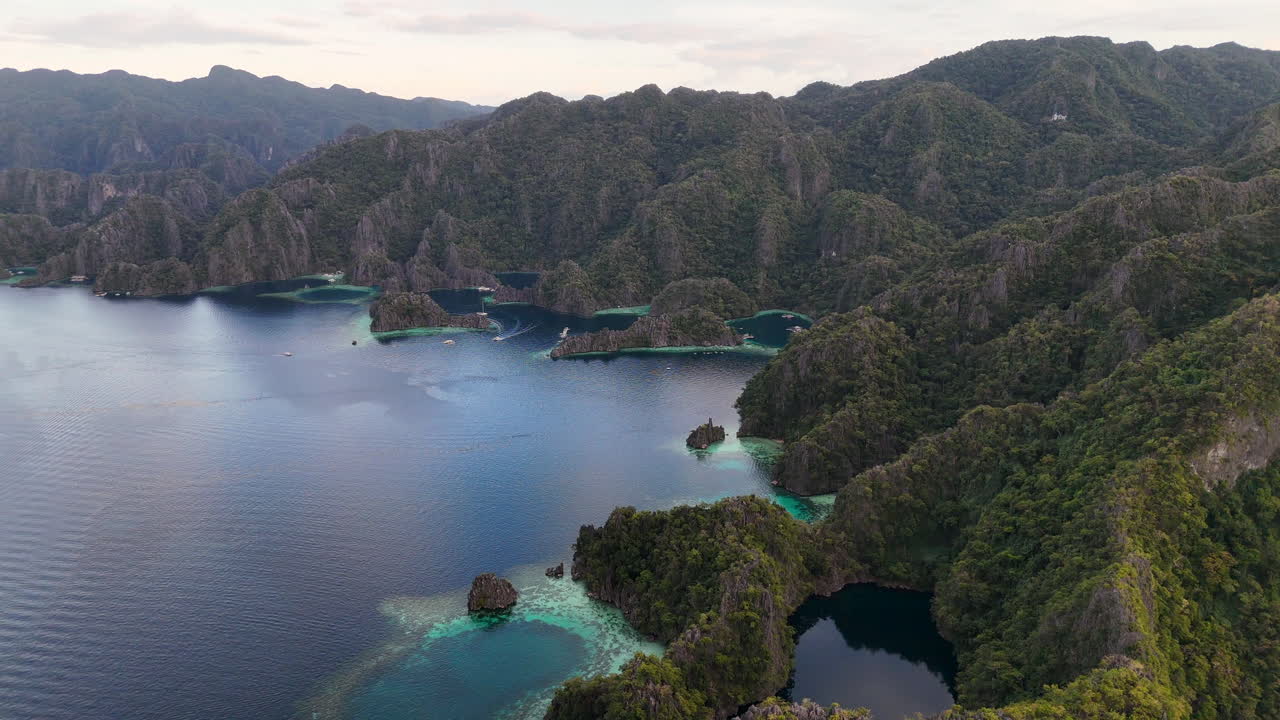Aerial drone view of Coron Island’s dramatic cliffs, tropical greenery, and idyllic turquoise waters, Philippines. Slow revealing shot.