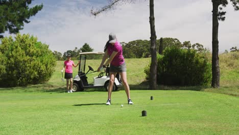 Two-caucasian-women-playing-golf-one-taking-shot-from-bunker