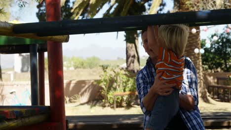 father assisting son on climbing monkey bars at playground 4k