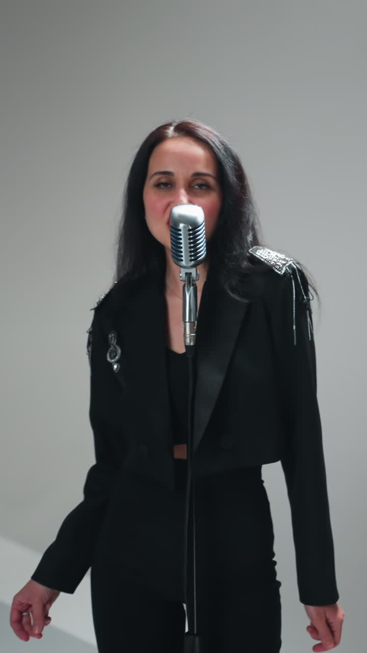 elegante vocalista femenina en traje negro actúa en un micrófono vintage con el tecladista en el fondo mientras la cámara se aleja