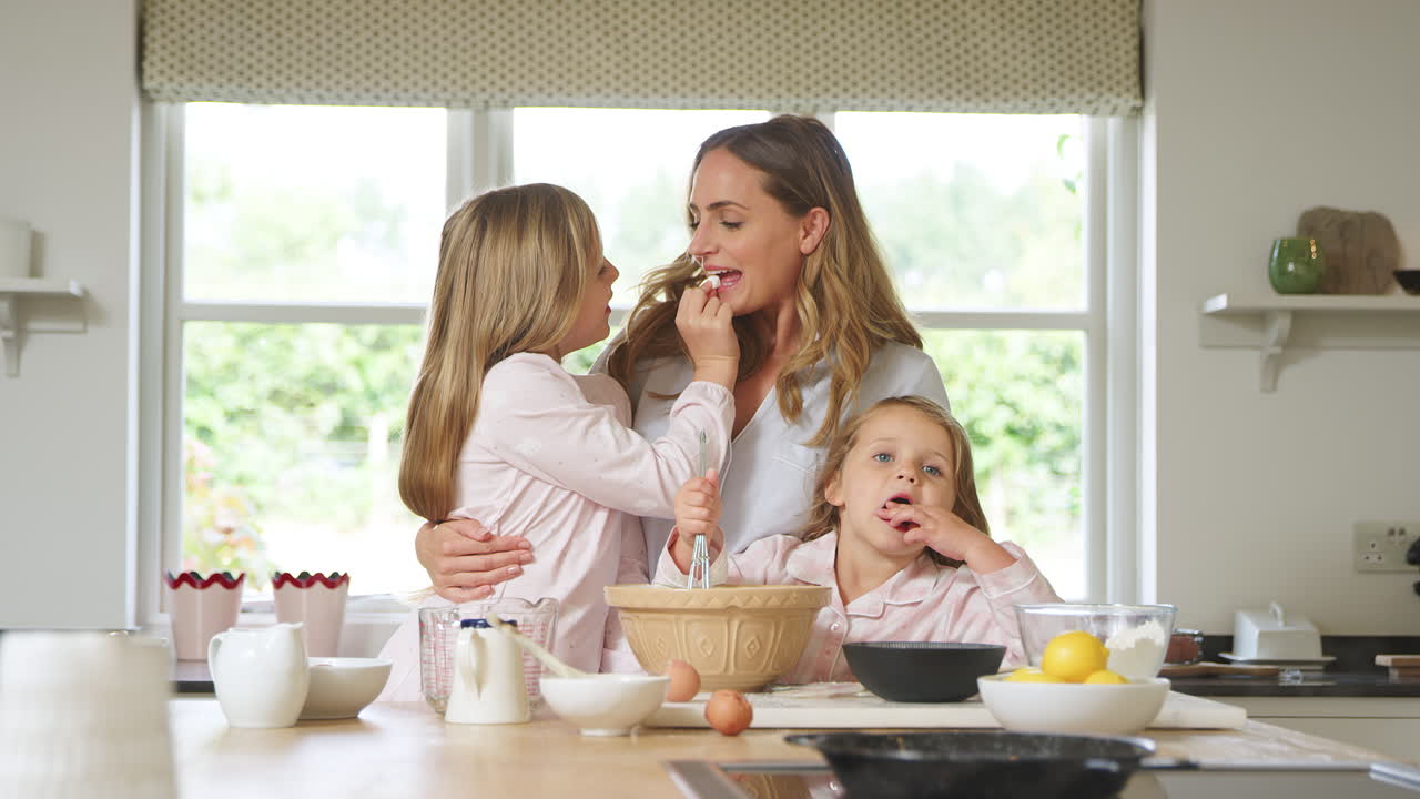 madre y dos hijas con pijama horneando en la cocina en casa juntas
