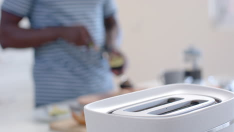 African-american-man-preparing-avocado-toasts-in-sunny-kitchen,-slow-motion