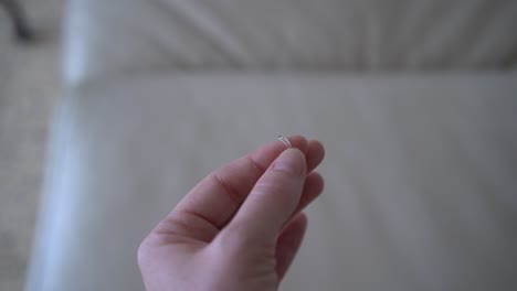 a woman holding a cat's claw that was found in the house, in the background is an old white leather sofa