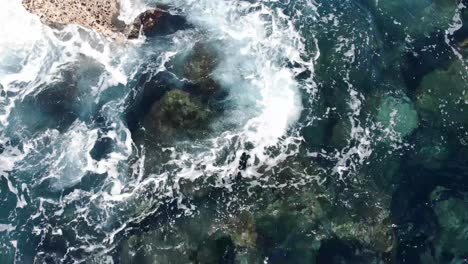 turtle takes a surface breath and dives down towards rocks under the ocean