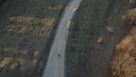 un ciclista solitario viaja a lo largo de un camino de tierra a través de un paisaje rural capturado desde arriba