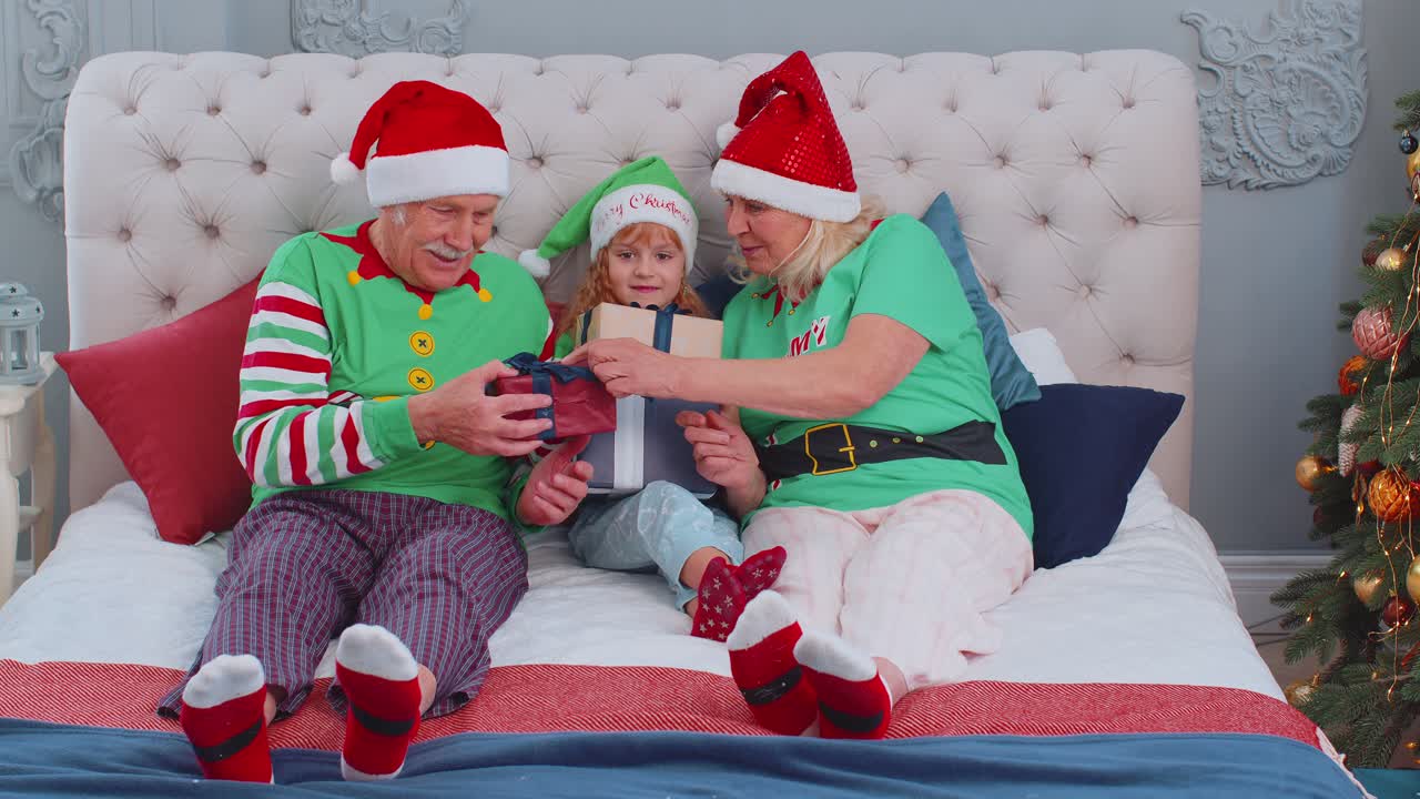abuelos mayores con nieto niña niño exhcanging regalos en el dormitorio de casa cerca del árbol de navidad