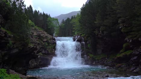 Waterfall-on-cliff-in-mountains-near-trees