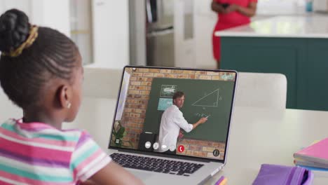 african american girl using laptop for online lesson with biracial male teacher on screen