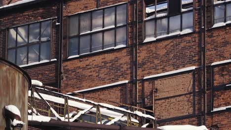 old red brick building with large broken windows, covered in snow