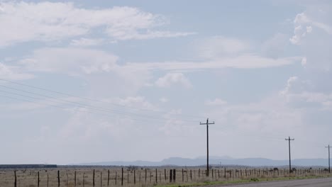 train passing in the distance with telephone poles in the foreground, surrounded by endless texas skies