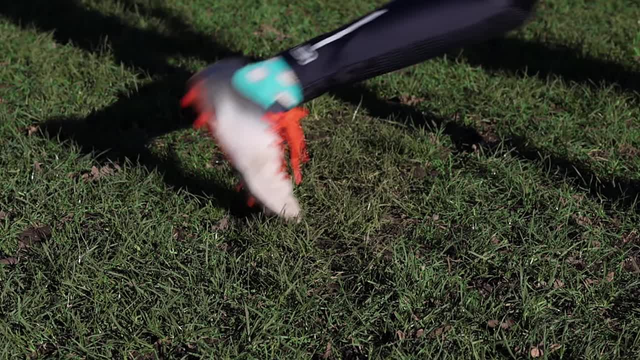 близкий взгляд на молодую девушку, пинающую футбол снаружи в парке