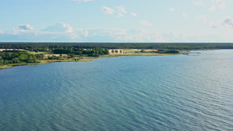 Vom-Meer-Aus-Seitlich-Auf-Felder-Und-Bäume-Am-Ufer-Zufliegen