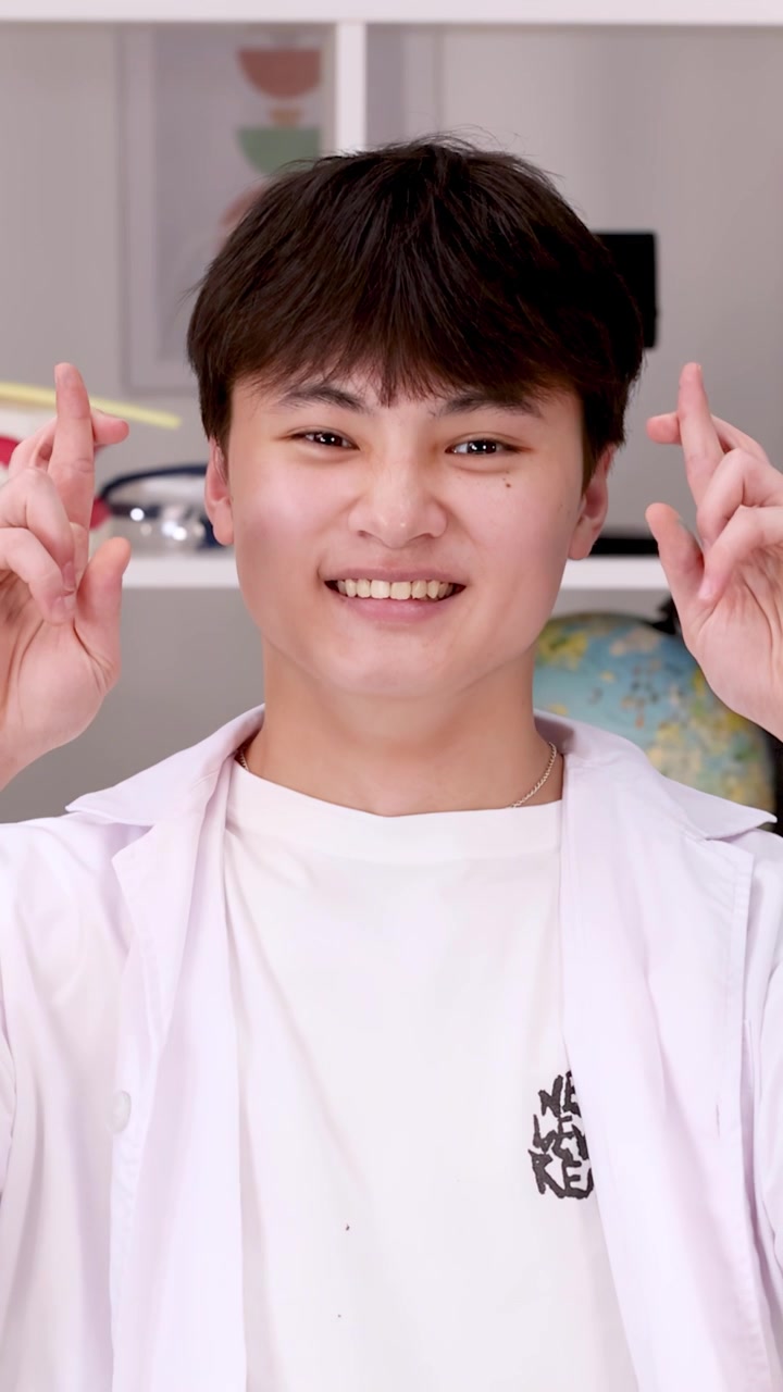A smiling student in a science lab crosses his fingers, hoping for a positive result.