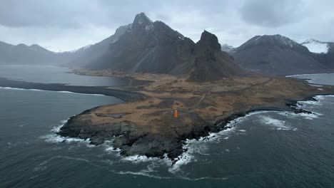 iceland dramatic coastline in the eastern fjords with orange lighthouse on iceland's ring road