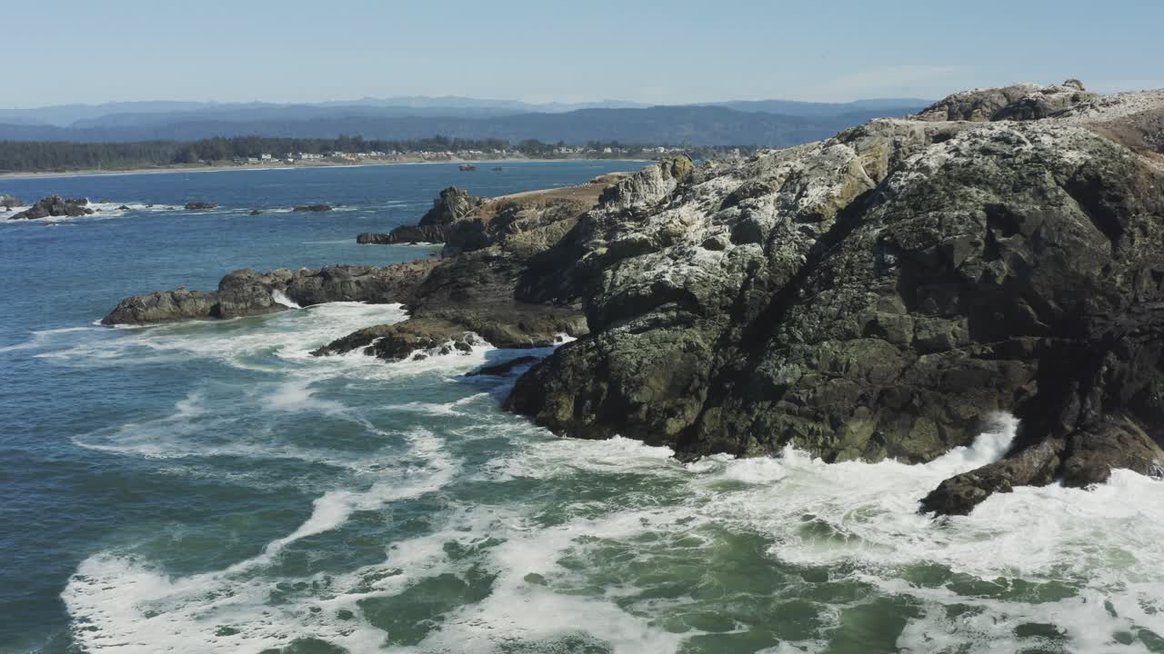 Stationary aerial drone footage of crashing ocean waves on a large boulder, which sits in the Pacific ocean, Oregon