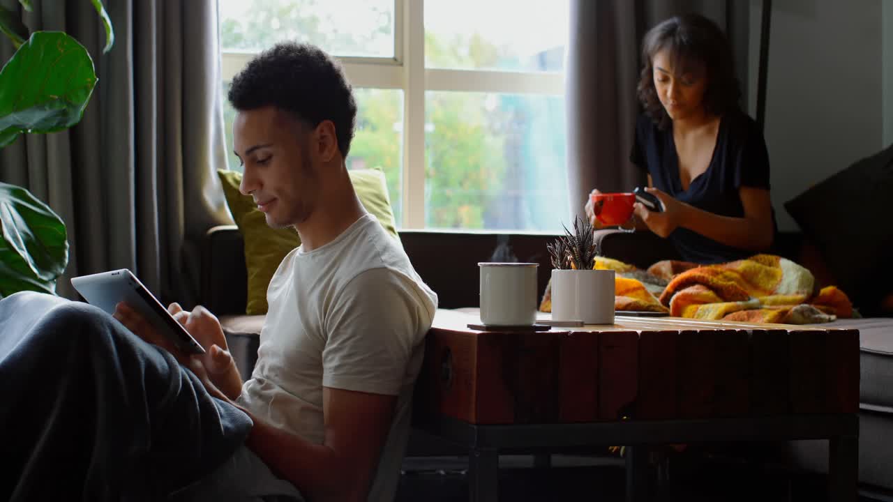 vista lateral de un joven asiático usando una tableta digital en la sala de estar en casa 4k