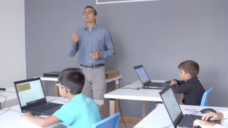 computer science teacher explaining lesson to children