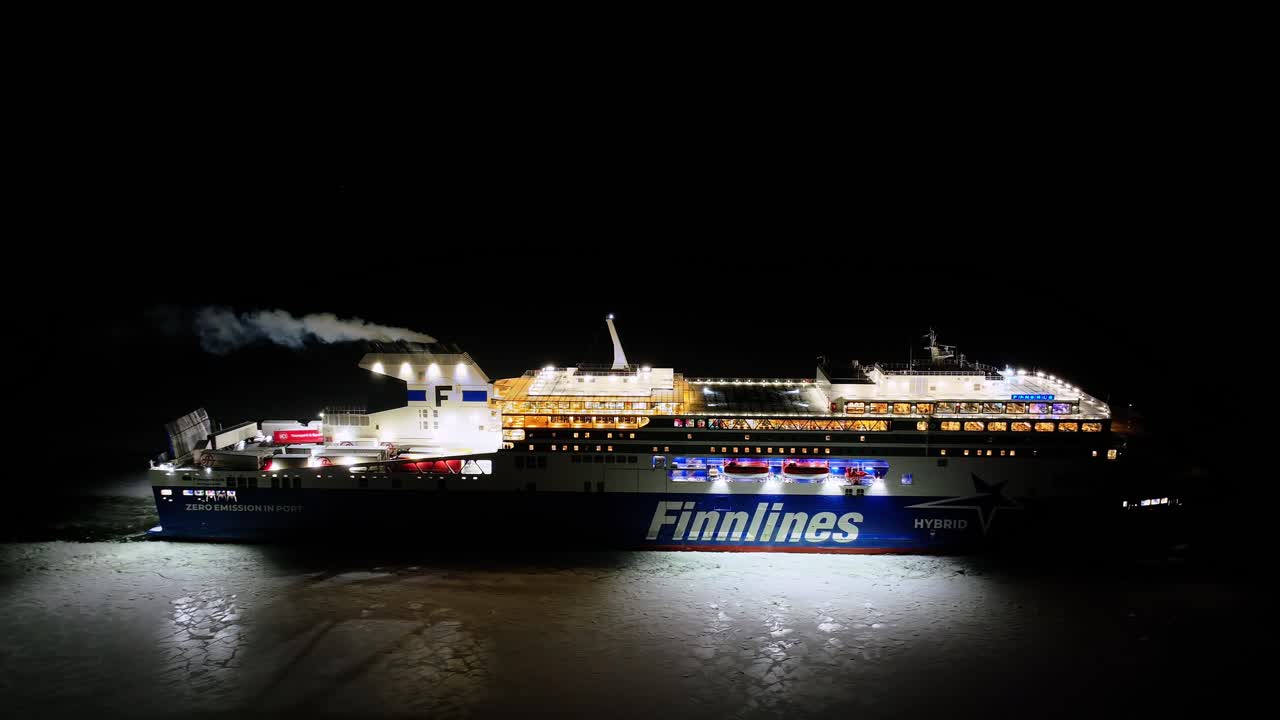 Finnlines hybrid roro ship FINNSIRIUS moving through ice covered sea at night. Following aerial side view.