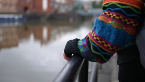 close up shot of a woman hand in a log sleeve sweater holding the rail of an iron fence