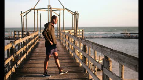 Afroamerikanischer-Männlicher-Jogger,-Der-In-Der-Sonne-Auf-Dem-Pier-Am-Strand-Läuft-4k