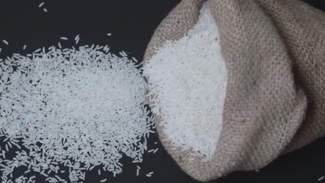 slow motion rice pours out of falling sack on black table