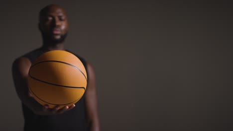 Studioporträtaufnahme-Eines-Männlichen-Basketballspielers,-Der-Den-Ball-In-Richtung-Kamera-Hält