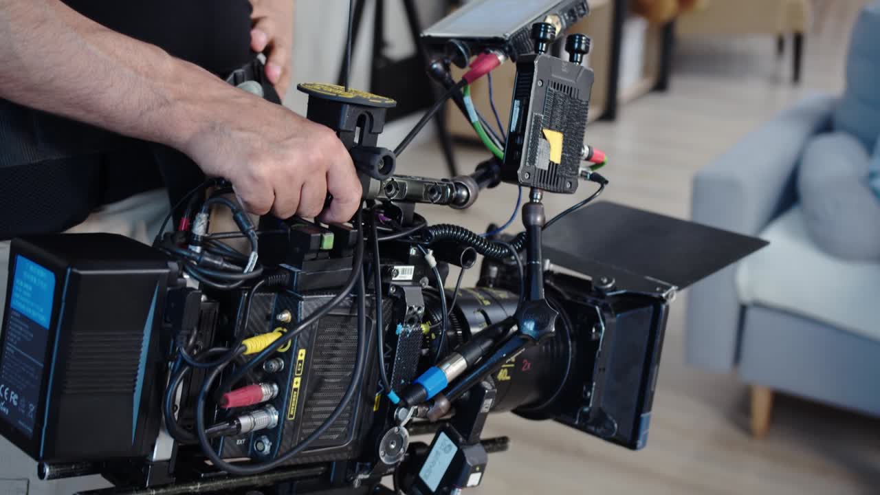 The operator shoots on a professional camera holding it in his hands on weight, monitors the shooting process through the manitor. Sophisticated technical equipment of a videographer's camera