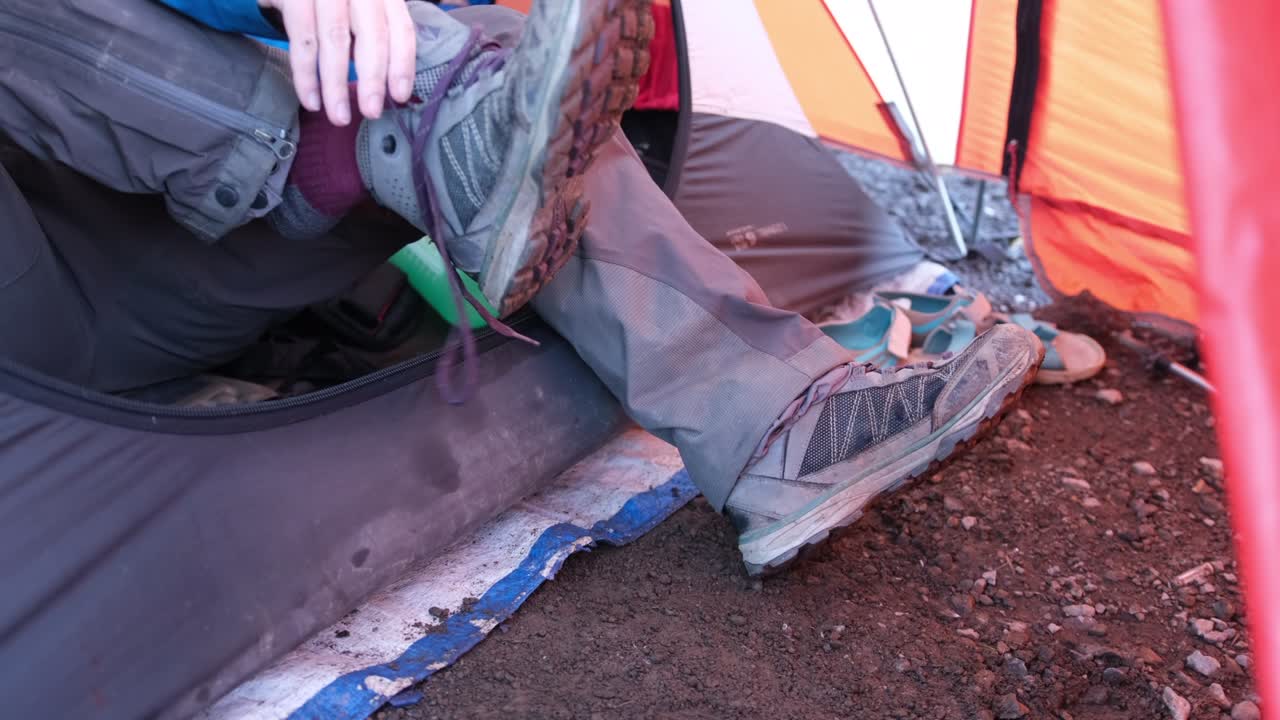 텐트 에 앉아 있는 관광객 이 신발 을 고 있다