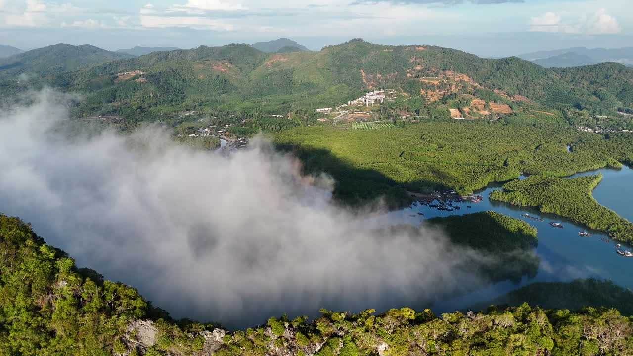 Aerial of tropical forest canopy and mist over Phuket hills during sunrise, Thailand
