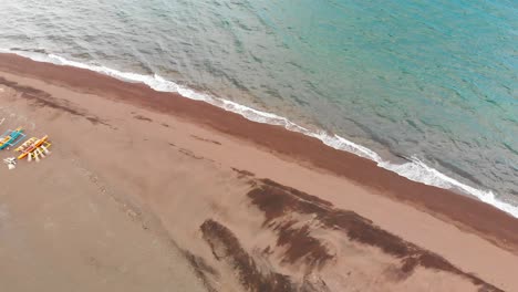 Antena-De-Drones-Sobre-Una-Playa-De-Arena-Tropical-Que-Pasa-Sobre-Un-Pueblo-De-Pescadores-Con-Botes-Bomba