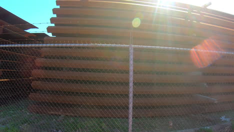 driving along a chain linked fence that surrounds piles of panels for building the border wall