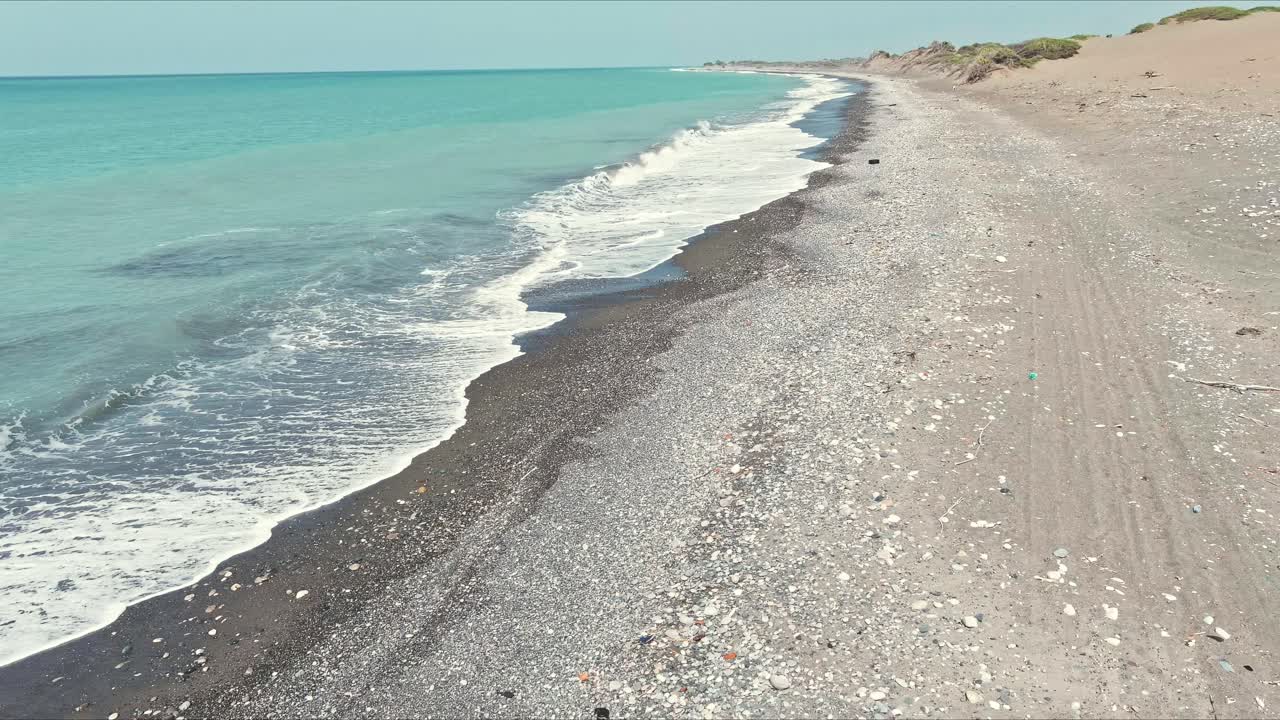 вид с воздуха низко над волнами и скалами на пляже дюн бани в доминиканской республике - реверс, снято с дрона