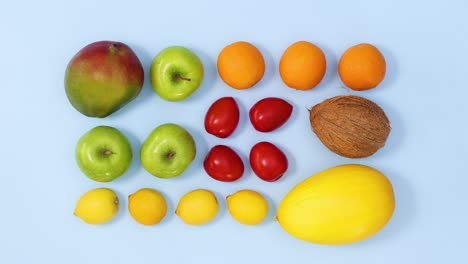 creative vibrant layout made of fresh fruits in different colors move on light blue background. stop motion flat lay