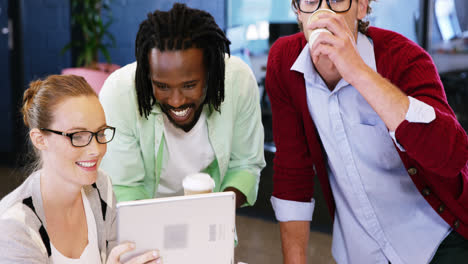 colegas discutiendo sobre la tableta digital mientras tienen una taza de café