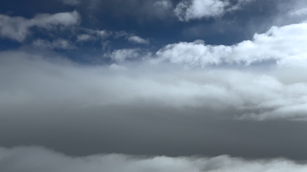 Relaxing aerial view captured from a jet cockpit while flying peacefully between mulilayered ethereal clouds under a deep blue sky