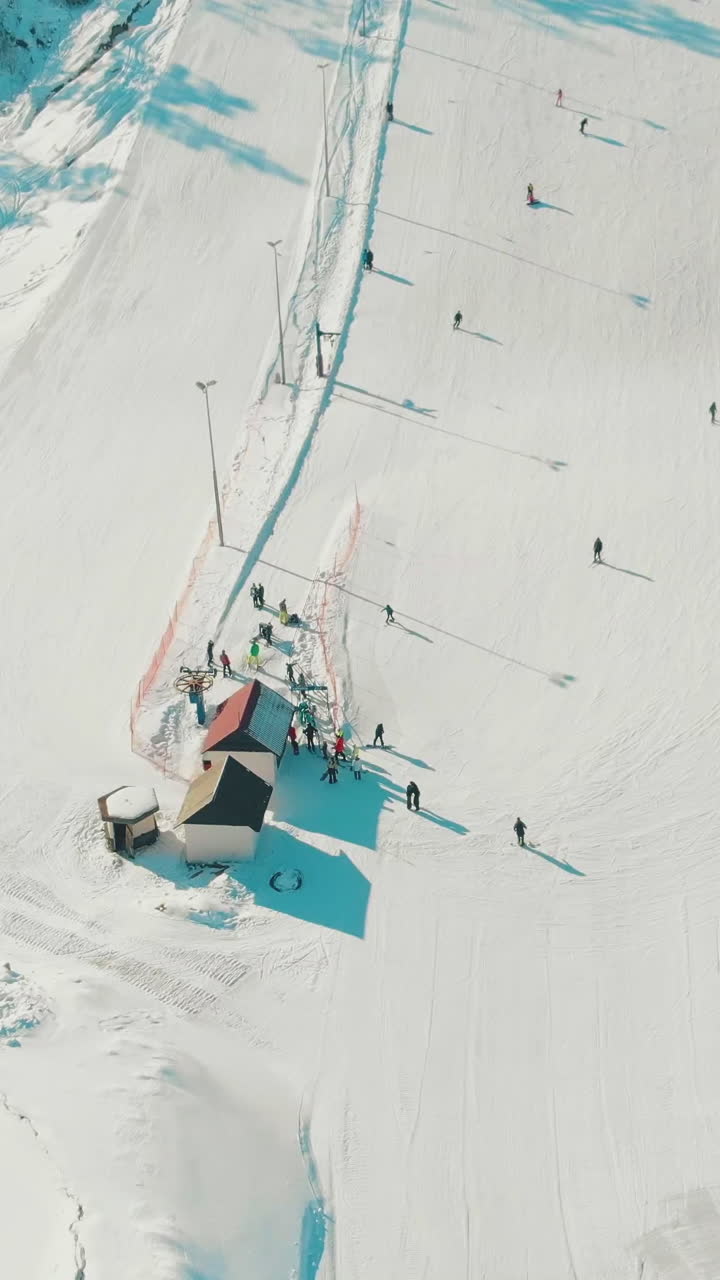 people on active holidays ski and snowboard at red roof building of lift top station on winter day upper vertical view
