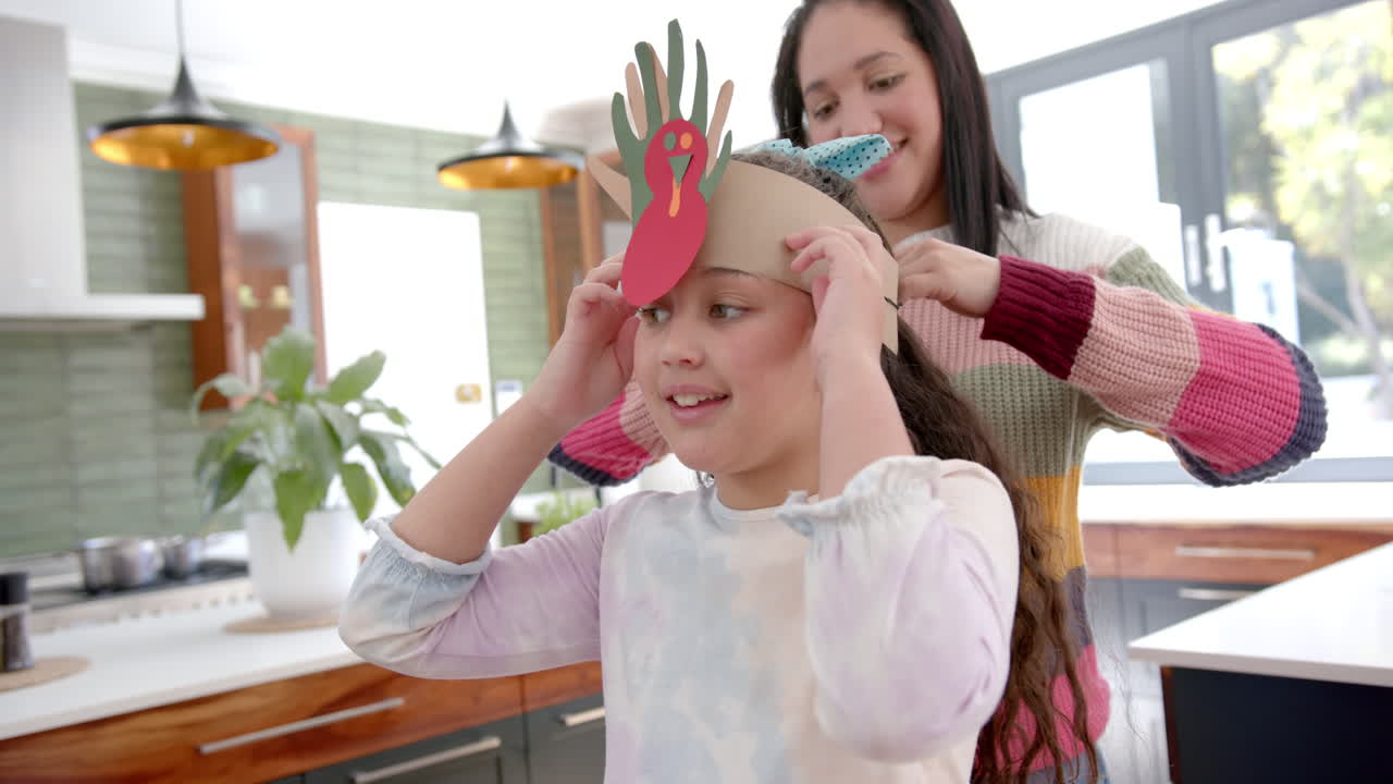 행복 한 혼혈 어머니 와 딸 이 종이 밴드 로 놀고 빛 이 있는 거실 에서 미소 짓고 있다