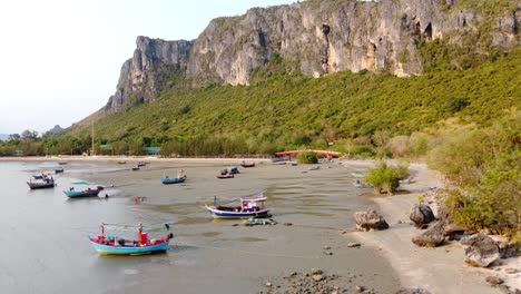 aerial footage of colorful boats on the sand at low tide along the tropical coastline of khao ta mong lai bay, thailand