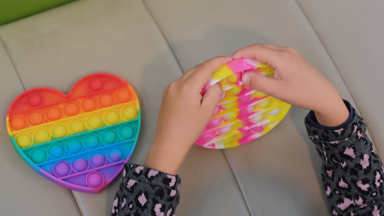 Child Girl Plays with Colorful Pop It Fidget Toy