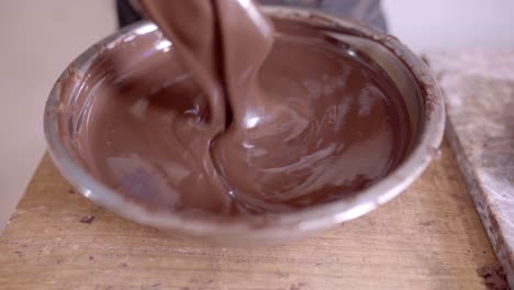 crop anonymous person stirring melted chocolate in bowl